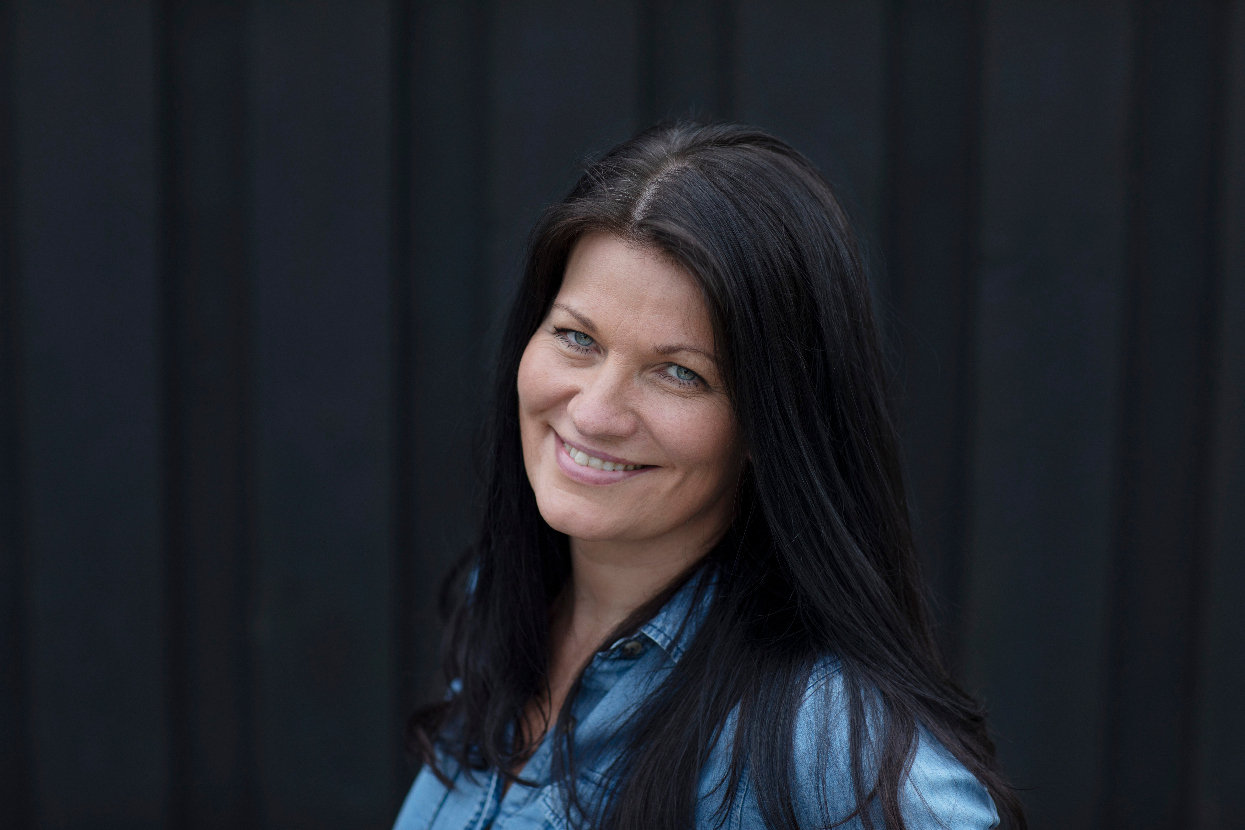 Two women sitting at a modern table talking with a city view behind them.